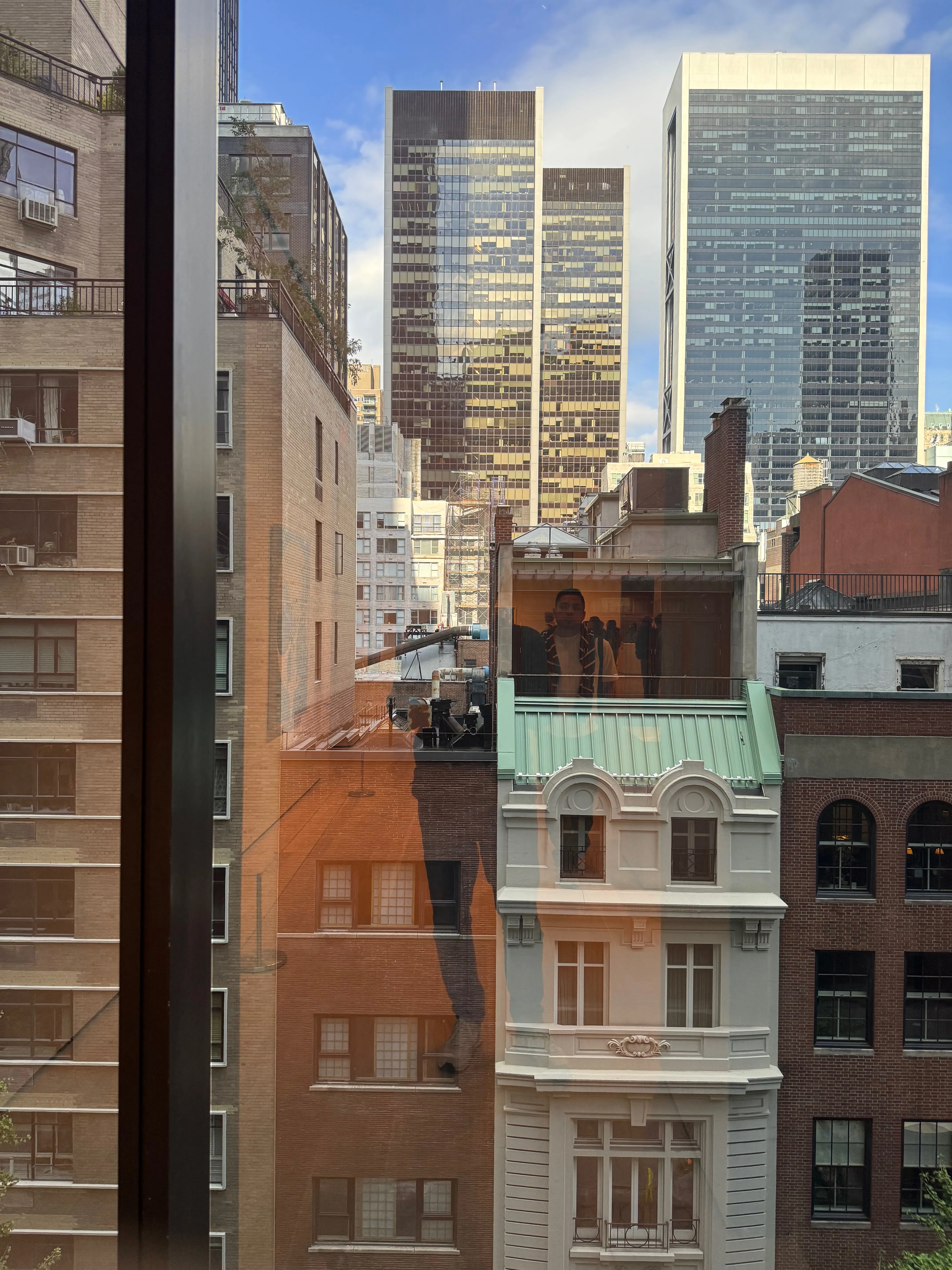 Photo of my reflection on a glass in front of Manhattan buildings