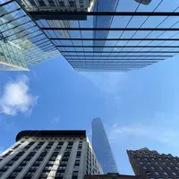 Photo of the sky with a building with a glass exterior mirroring a taller building