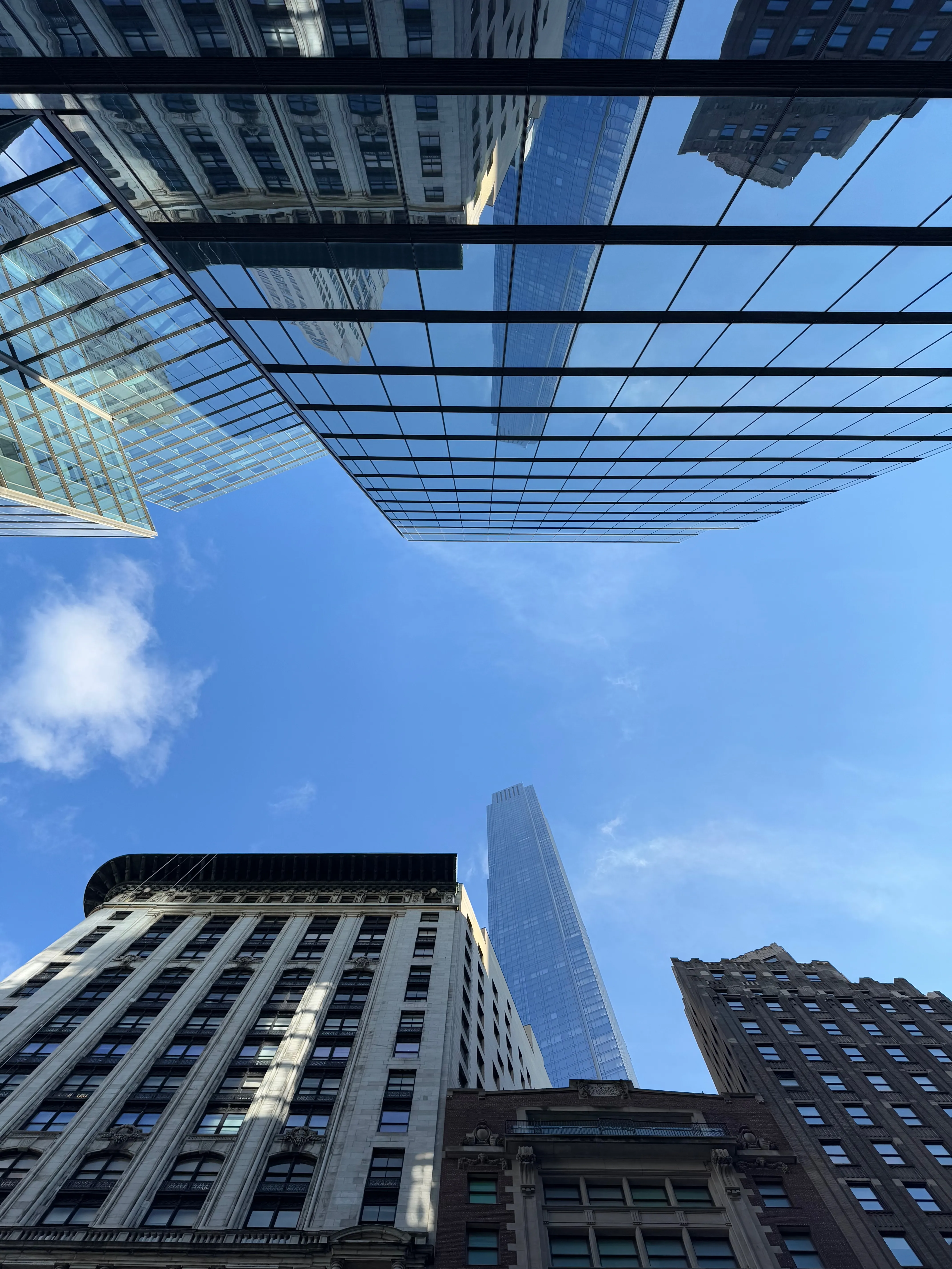 Photo of the sky with a building with a glass exterior mirroring a taller building